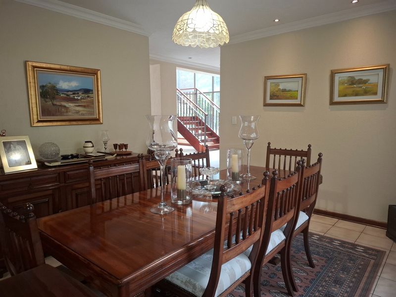 A formal dining room featuring tiled flooring, crown molding, and a view through to a staircase with a wooden handrail.