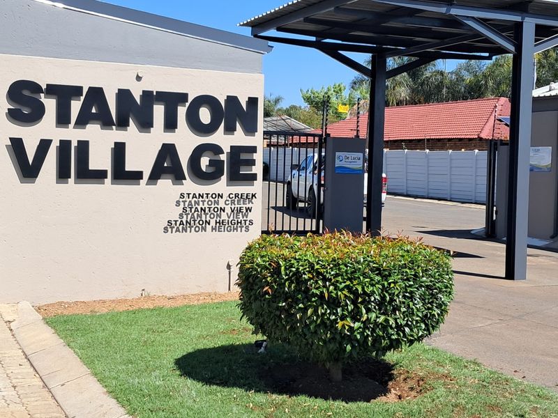 The entrance to Stanton Village featuring a secure gated access point, paved driveway, and covered carport structure.