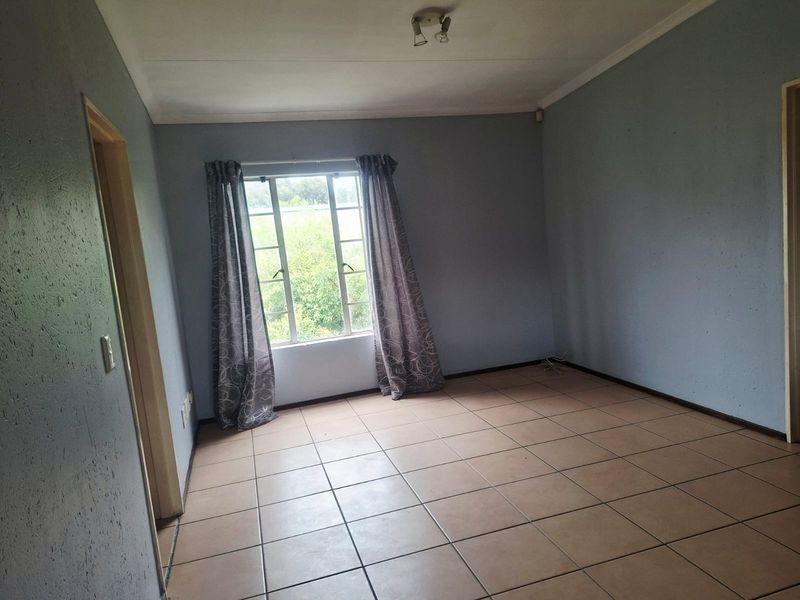 An empty bedroom featuring tiled flooring, a window with security bars, and neutral wall paint, offering a blank canvas for personalization.