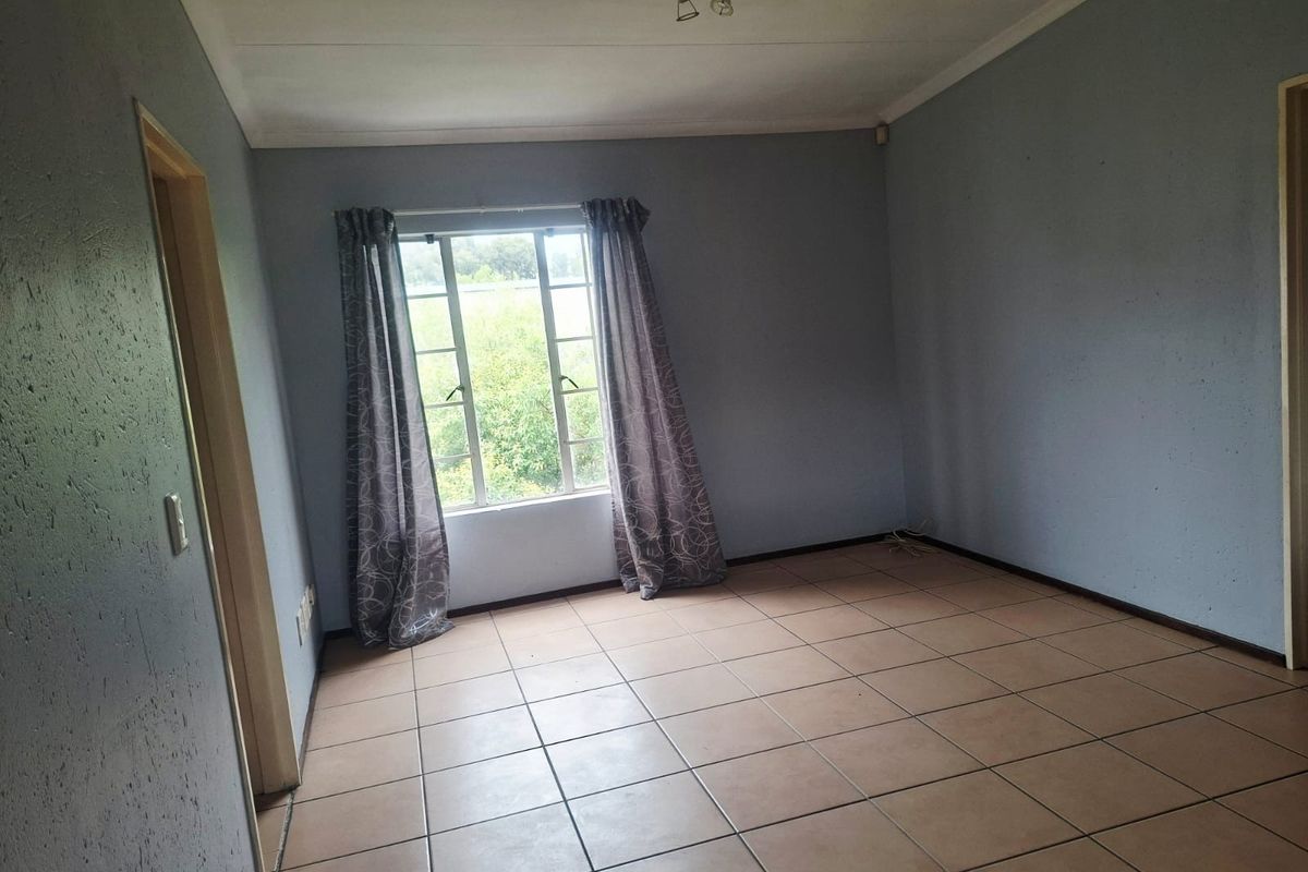 An empty bedroom featuring tiled flooring, a window with security bars, and neutral wall paint, offering a blank canvas for personalization.