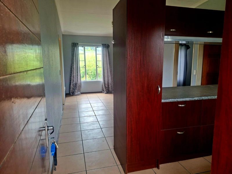 An open-plan living area featuring tiled flooring, built-in cabinetry with a laminate countertop, and natural light from a window.