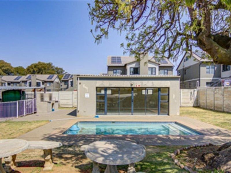 Outdoor pool area featuring a swimming pool, paved surround, built-in braai, and established tree, set within a secure complex with boundary walling.