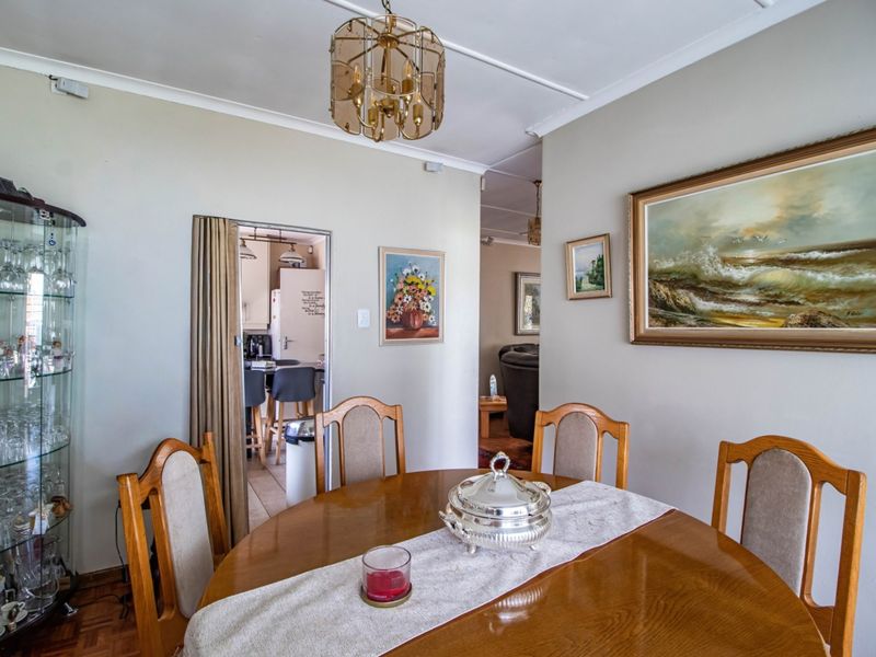 Dining room featuring parquet flooring and a central chandelier, with an adjacent view into the kitchen area.