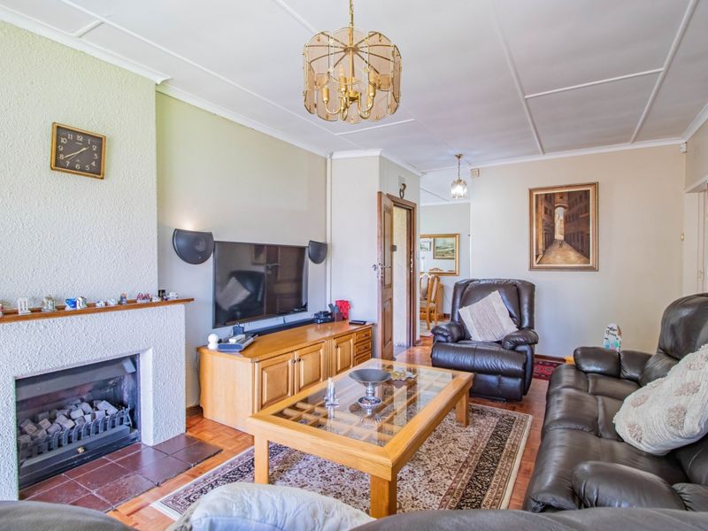 A comfortable living room featuring a fireplace with a tiled hearth, parquet flooring, and classic ceiling detailing.