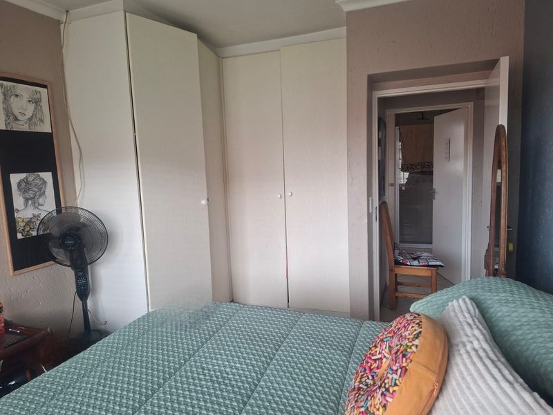 A bedroom featuring built-in cupboards and a doorway leading to an adjoining bathroom area.
