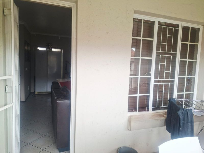 A covered balcony area featuring security gates and bars, providing access to the interior living space with tiled flooring.