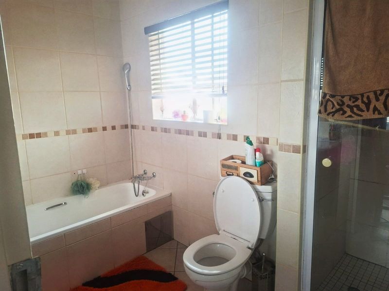 A functional bathroom featuring a bathtub, separate shower enclosure, and toilet with neutral wall and floor tiling.