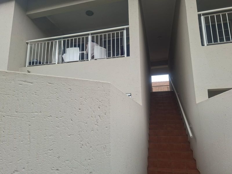 Exterior view of an apartment building featuring a tiled staircase leading to an upper-level balcony with a metal balustrade.