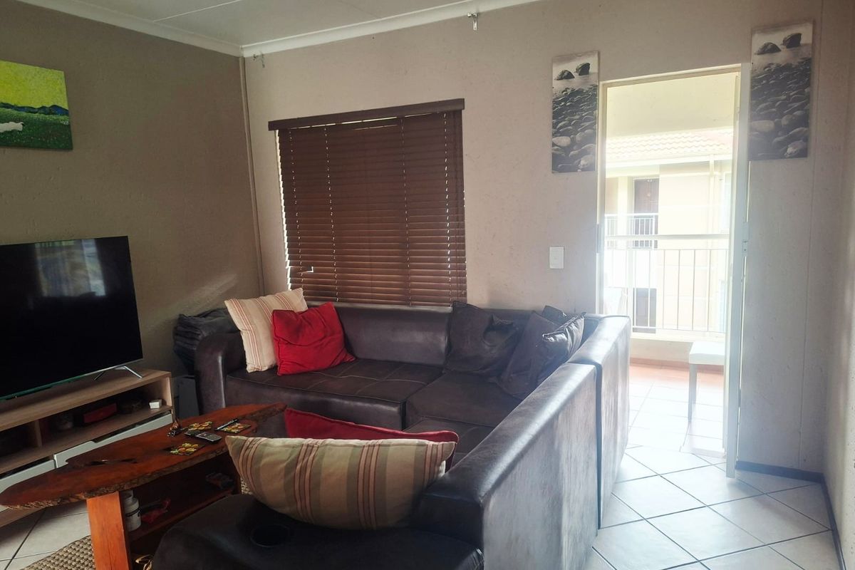 A living room featuring tiled flooring, venetian blinds, and direct access to an outdoor balcony area.