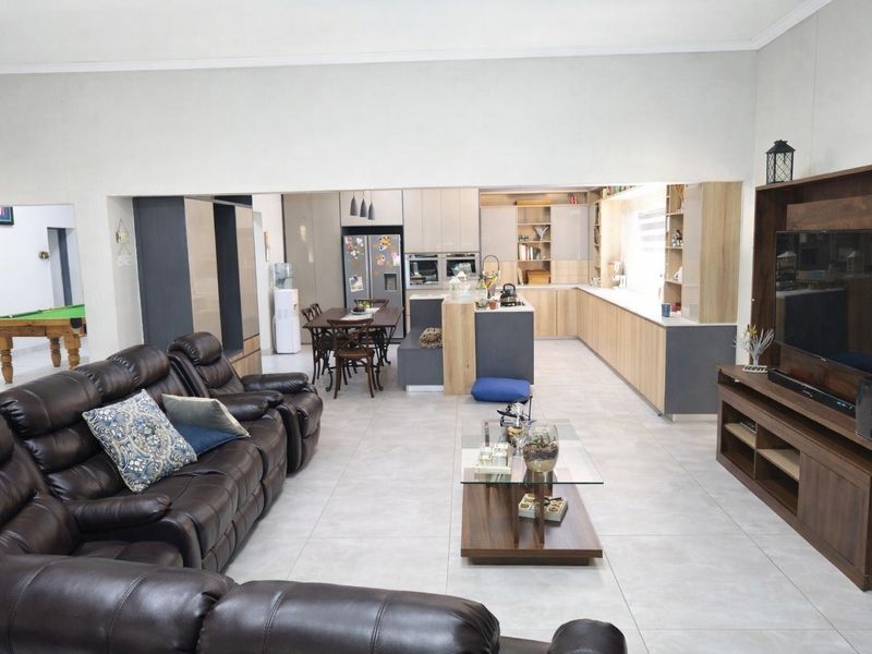 Spacious open-plan living area featuring a modern kitchen with built-in cabinetry, a central island, and large-format tiled flooring throughout.