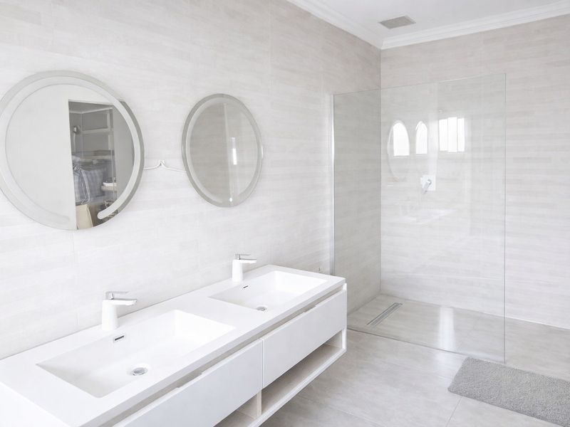Modern bathroom featuring a sleek double vanity with integrated sinks and a spacious walk-in shower with a frameless glass screen.
