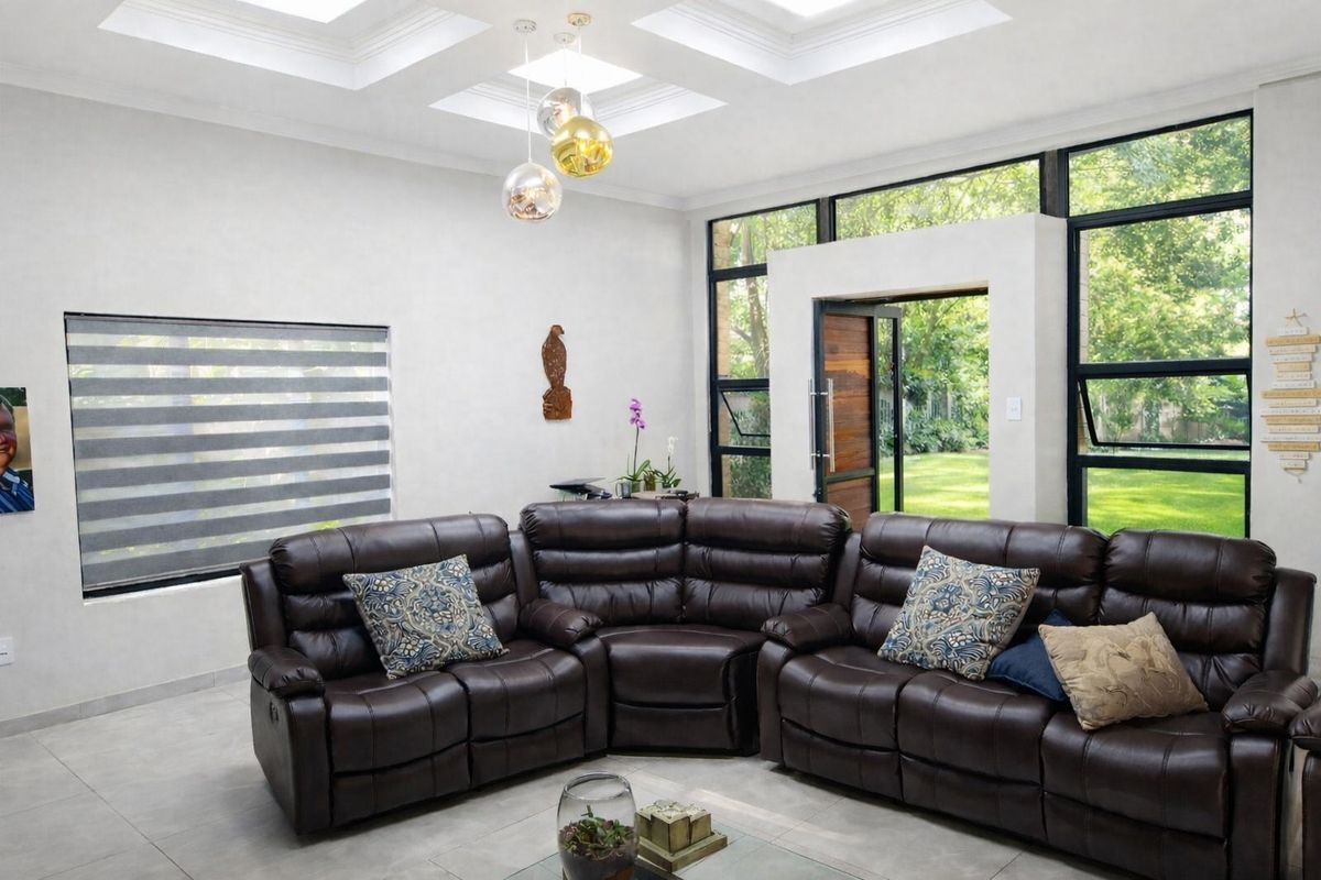 Spacious living room featuring a modern coffered ceiling, large black-framed windows providing garden views, and sleek tiled flooring.