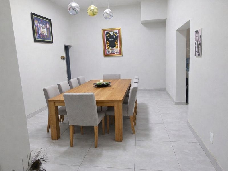A bright and spacious dining room featuring neutral tiled flooring and modern pendant lighting, providing a clean and functional space for family meals.