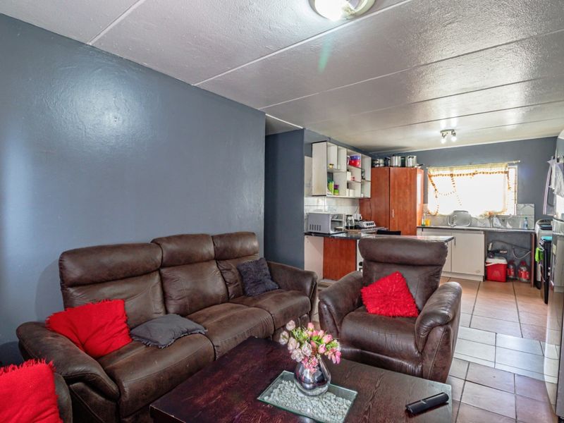 Open plan living area featuring tiled flooring and a functional kitchen with built-in cabinetry and sink.