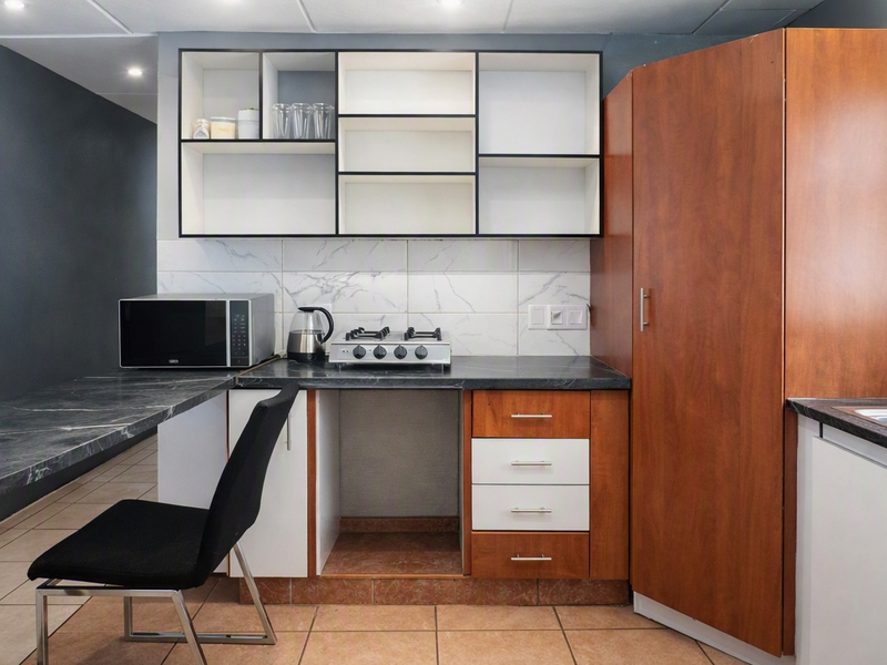 Compact kitchen featuring marble-effect countertops, gas hob, built-in cabinetry, and a breakfast bar extension, offering functional preparation space.