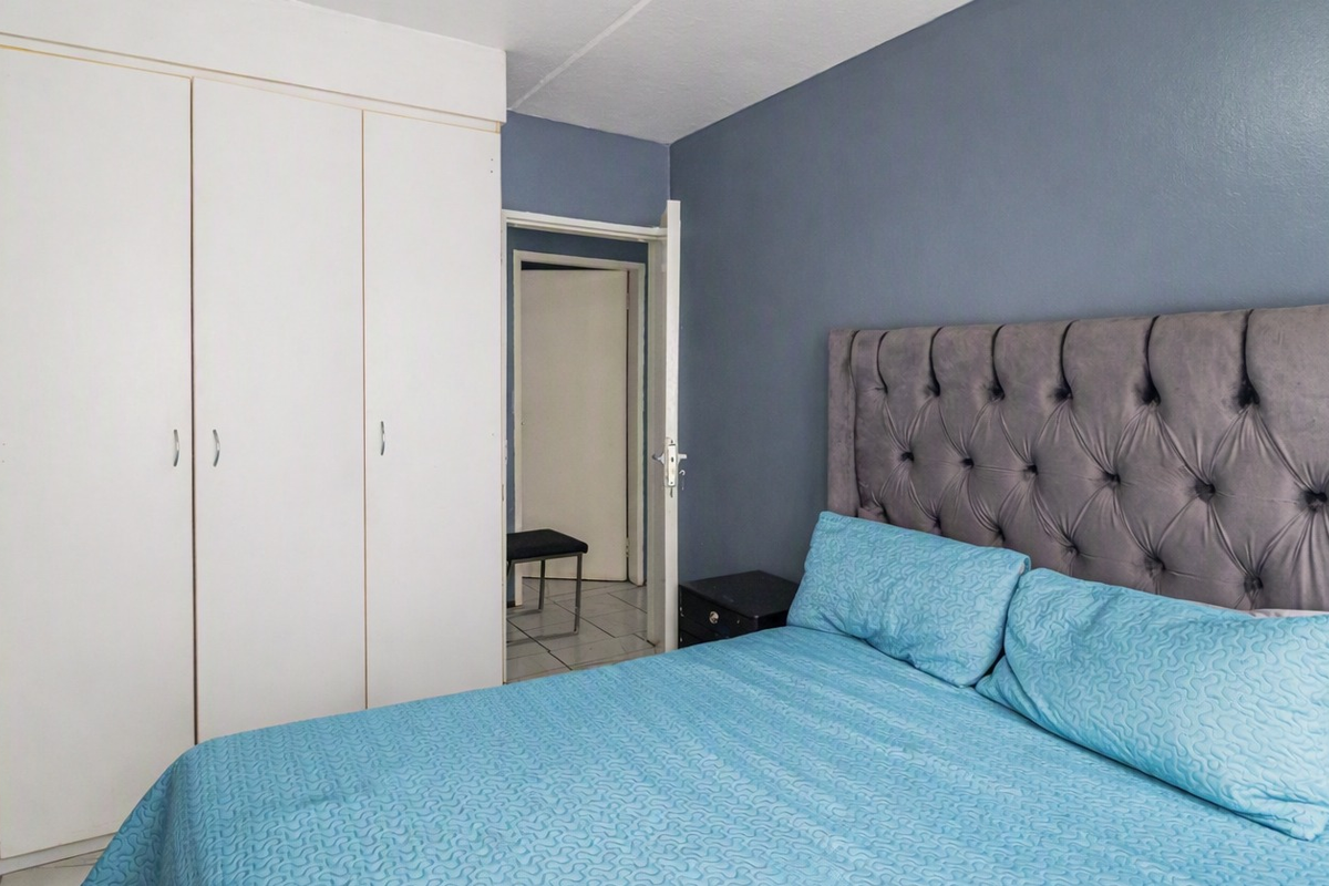 A bedroom featuring built-in cupboards and tiled flooring, providing a functional and clean living space.