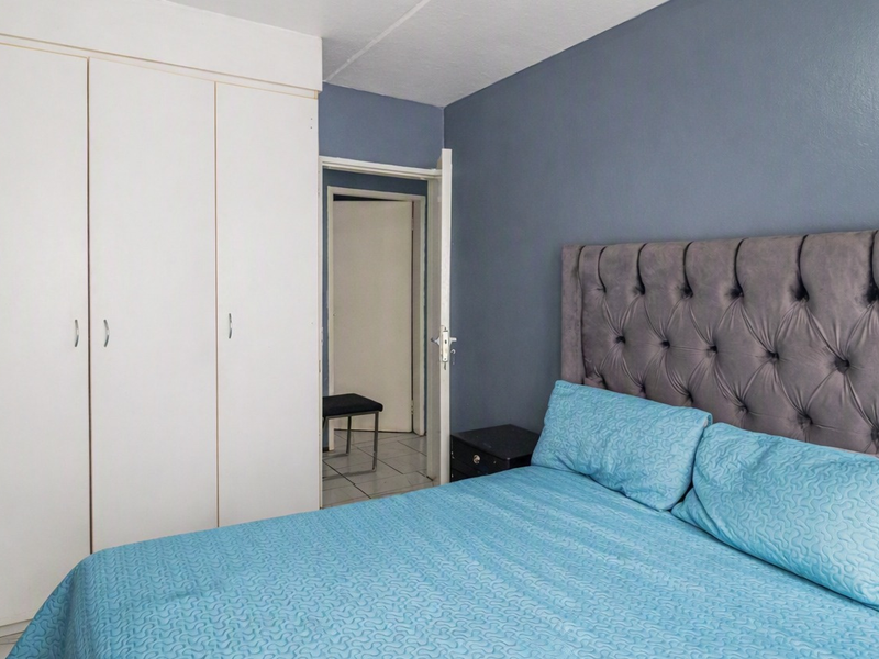 A bedroom featuring built-in cupboards and tiled flooring, providing a functional and clean living space.