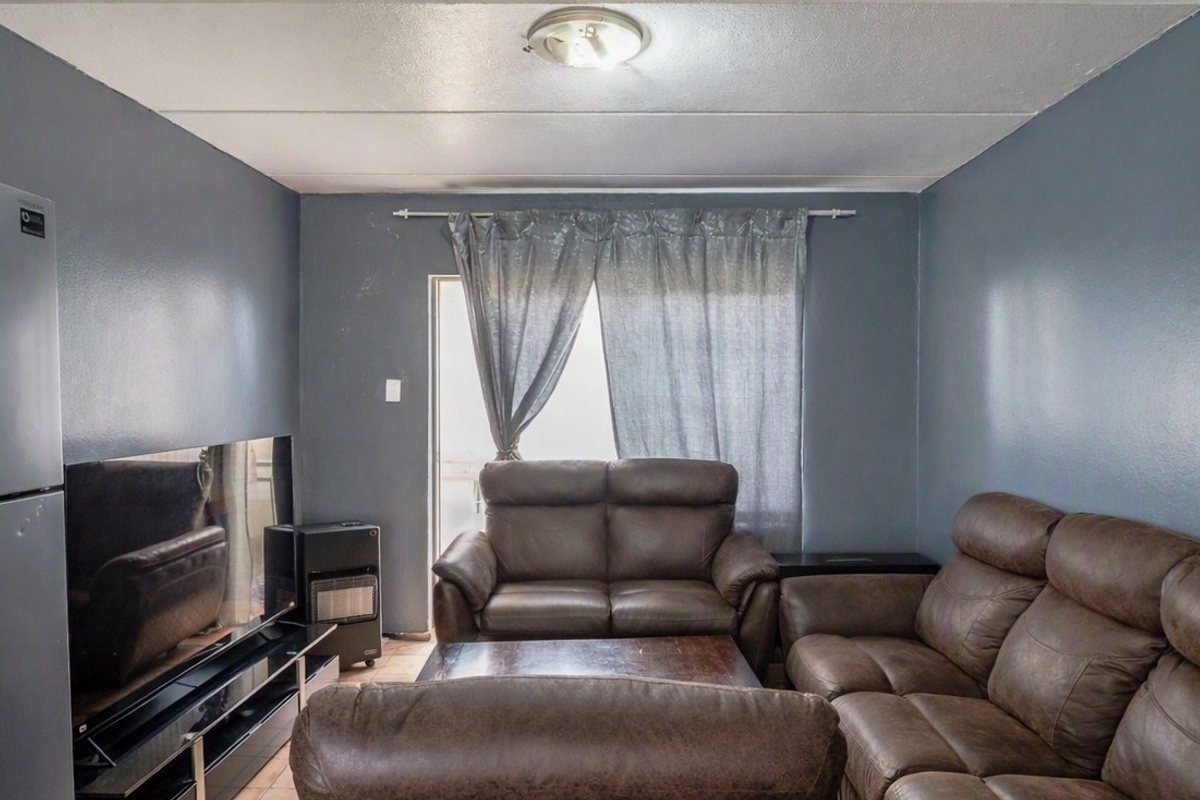 A living room featuring dark grey walls, a ceiling light fixture, and a sliding door leading to an outdoor area.