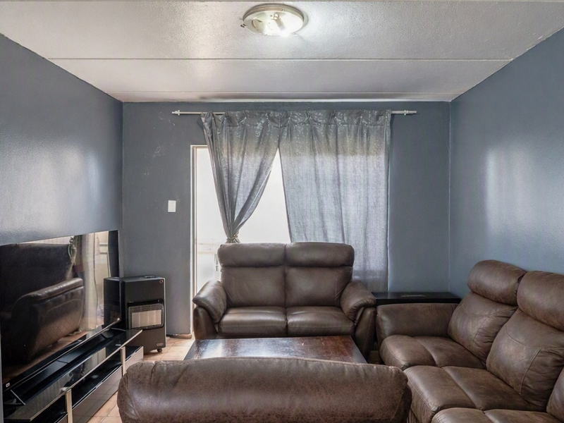 A living room featuring dark grey walls, a ceiling light fixture, and a sliding door leading to an outdoor area.