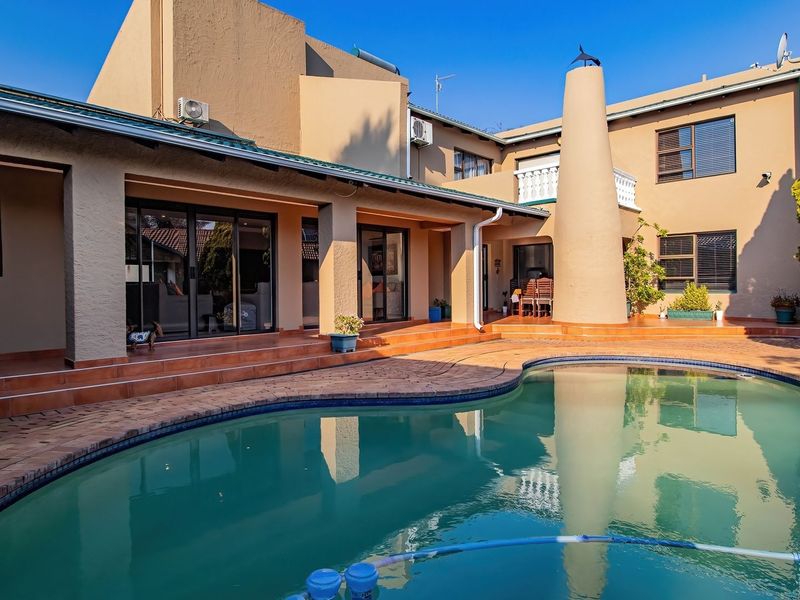 Spacious outdoor entertainment area featuring a swimming pool, brick-paved patio, and a distinctive outdoor fireplace, perfect for relaxed living.
