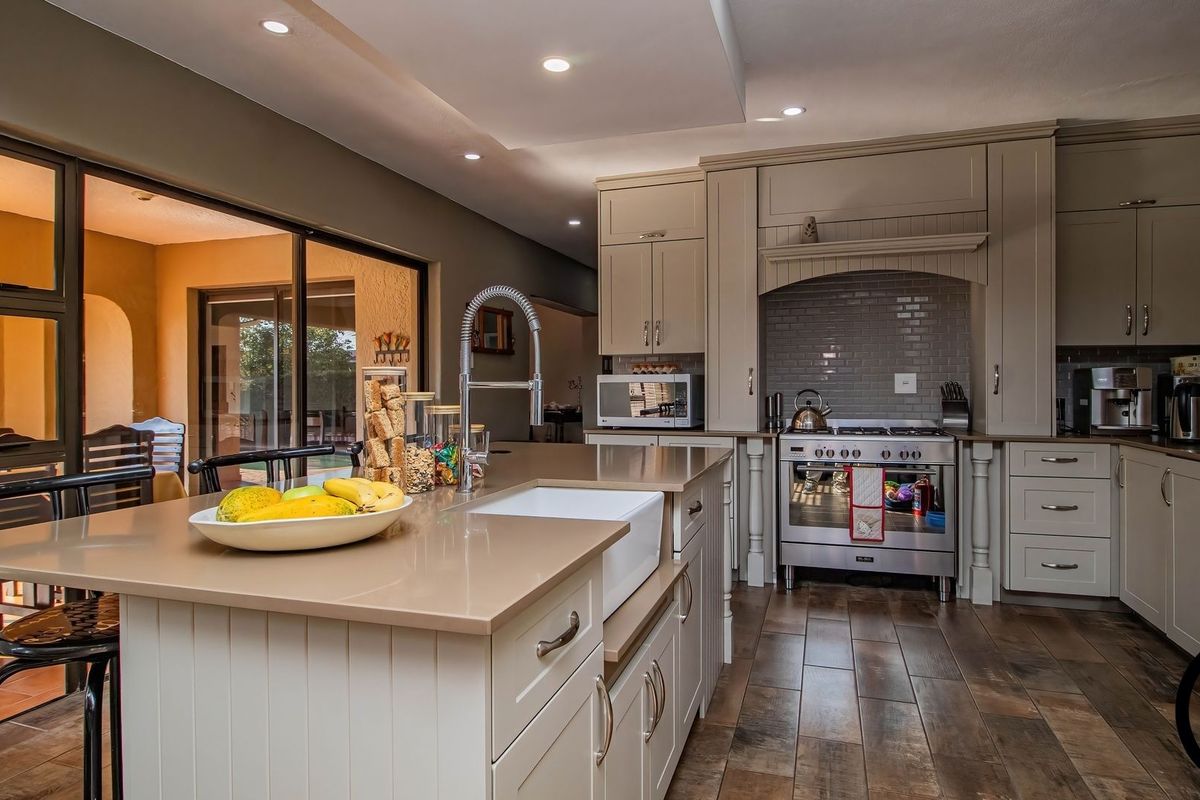 Modern kitchen featuring a central island with a farmhouse sink, high-end gas range, subway tile backsplash, and direct access to the outdoor patio area.