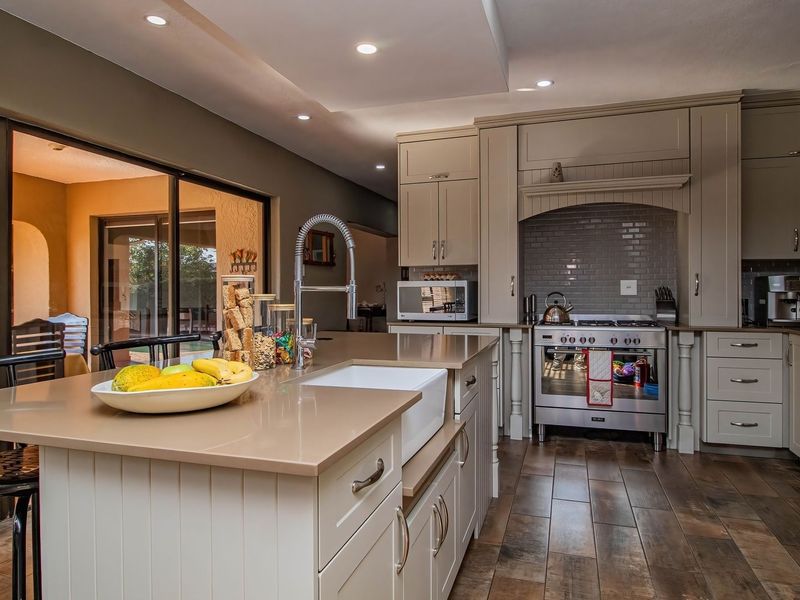 Modern kitchen featuring a central island with a farmhouse sink, high-end gas range, subway tile backsplash, and direct access to the outdoor patio area.