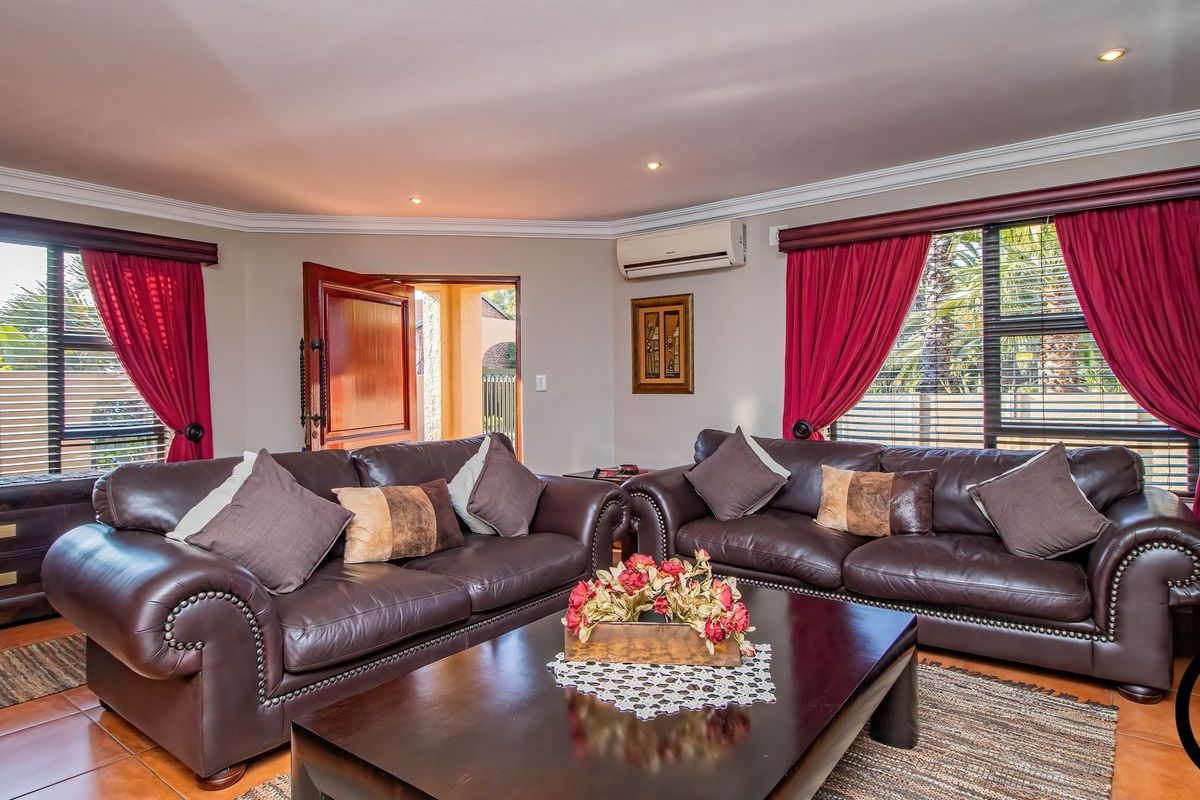 A comfortable living room featuring tiled flooring, recessed ceiling lighting, and a wall-mounted air conditioning unit, with access to an outdoor area.