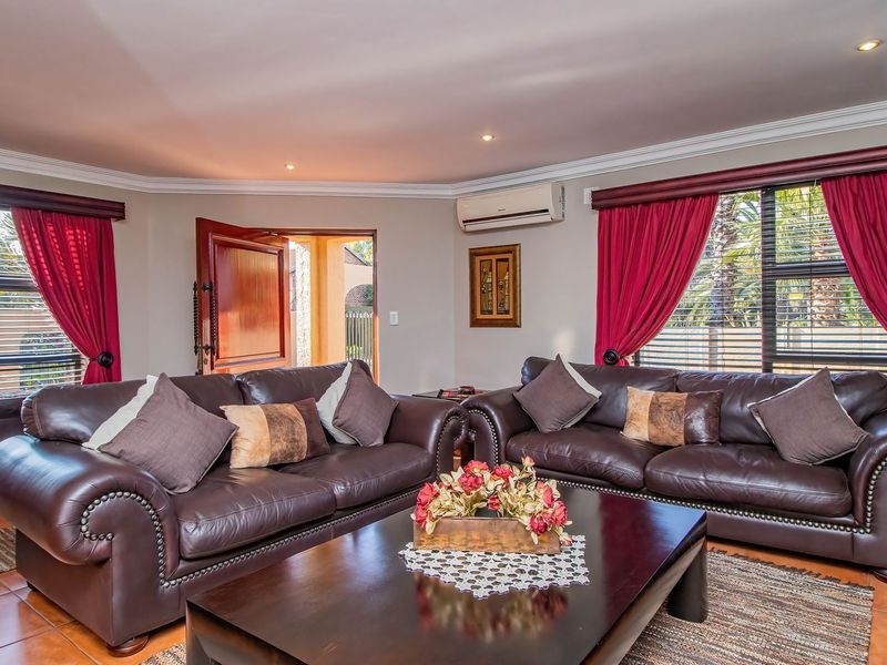 A comfortable living room featuring tiled flooring, recessed ceiling lighting, and a wall-mounted air conditioning unit, with access to an outdoor area.