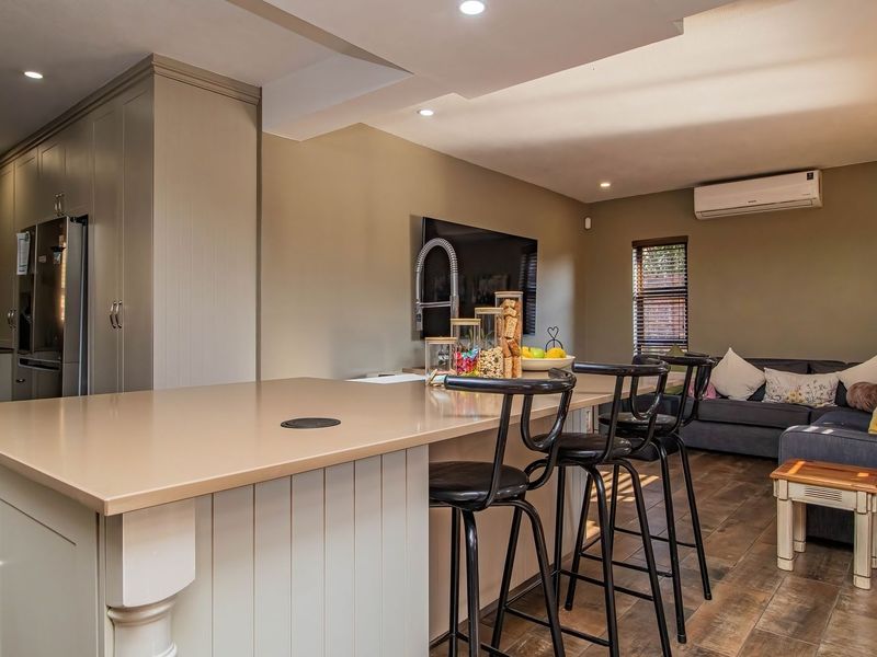Modern open-plan living area featuring a kitchen island with quartz countertops, recessed lighting, and laminate flooring, seamlessly integrated with the living space.