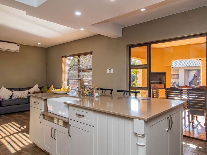 Spacious open-plan kitchen featuring a central island with a farmhouse sink, recessed lighting, and seamless flow to the outdoor patio area.