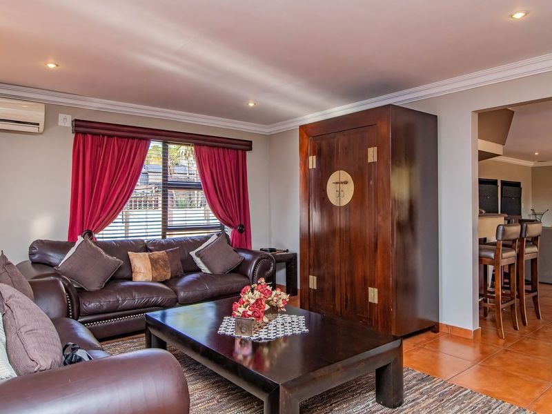 Spacious living room featuring tiled flooring, recessed downlighting, and a wall-mounted air conditioning unit, with an open-plan flow to the adjacent dining area.