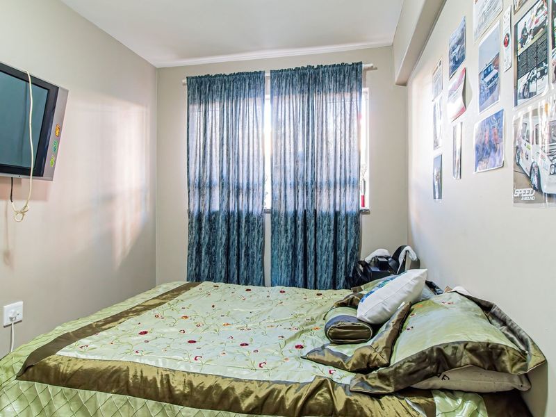 A standard bedroom featuring neutral wall finishes, a window with installed curtain tracks, and functional electrical points.