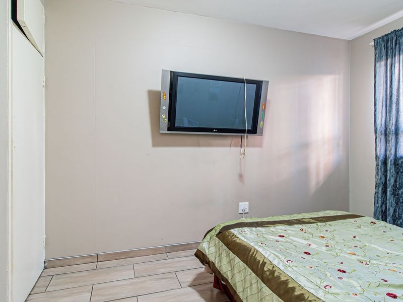 A bedroom featuring tiled flooring and a built-in cupboard, providing a functional space with neutral wall finishes.
