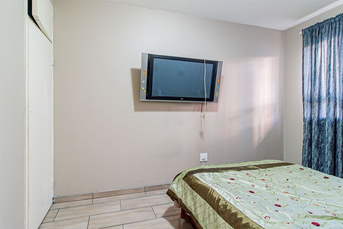 A bedroom featuring tiled flooring and a built-in cupboard, providing a functional space with neutral wall finishes.