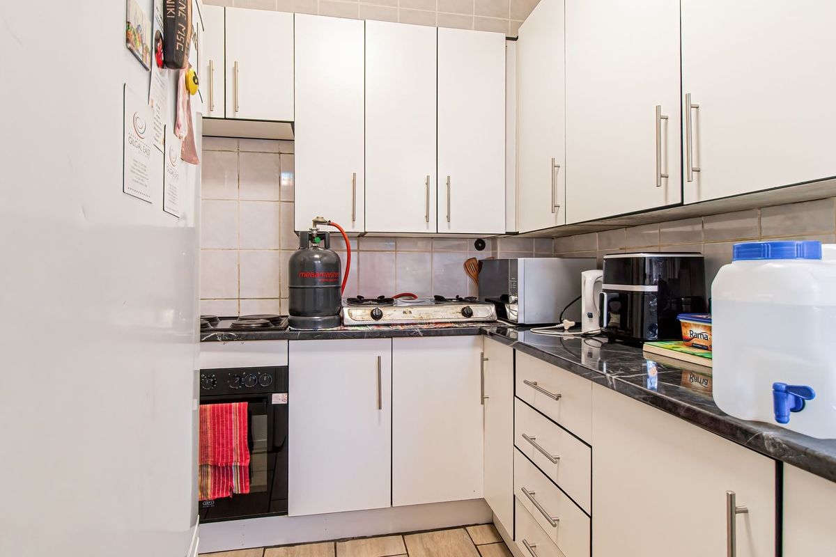 Compact kitchen featuring white cabinetry, dark laminate countertops, a built-in oven, and a gas hob with tiled backsplash.