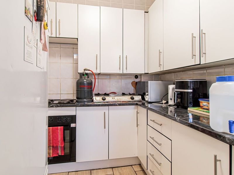 Compact kitchen featuring white cabinetry, dark laminate countertops, a built-in oven, and a gas hob with tiled backsplash.