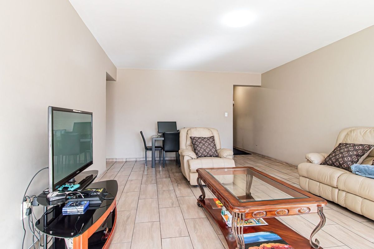 A spacious living area featuring neutral wall tones and tiled flooring, providing a versatile layout for comfortable daily living.