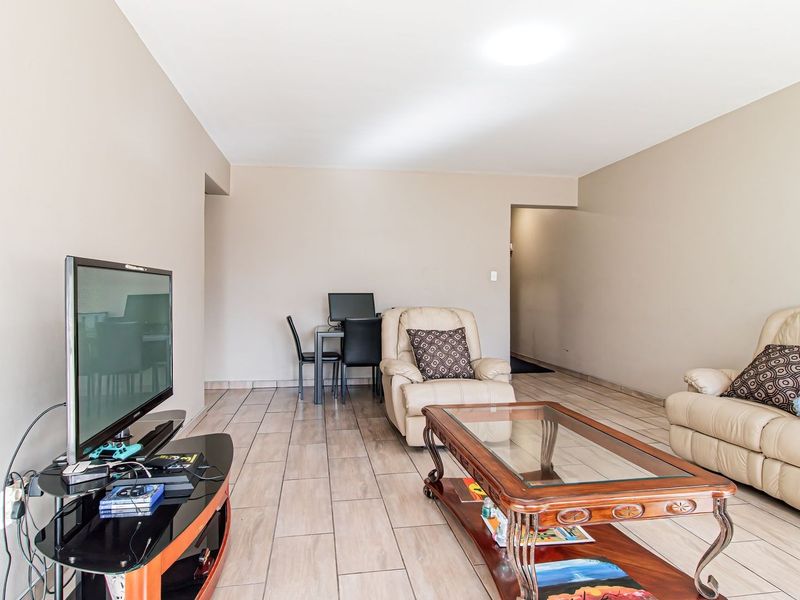 A spacious living area featuring neutral wall tones and tiled flooring, providing a versatile layout for comfortable daily living.