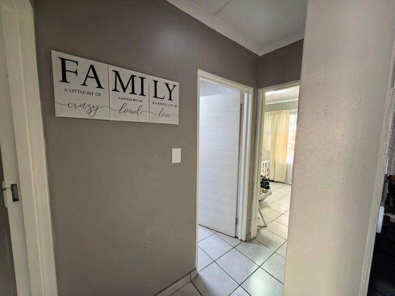 A functional hallway featuring tiled flooring and access to adjacent rooms, providing a clean and neutral transition space within the apartment.