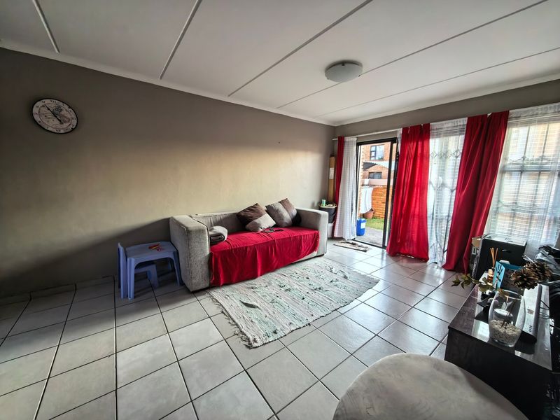 A living room featuring tiled flooring and a sliding glass door providing access to an outdoor area.