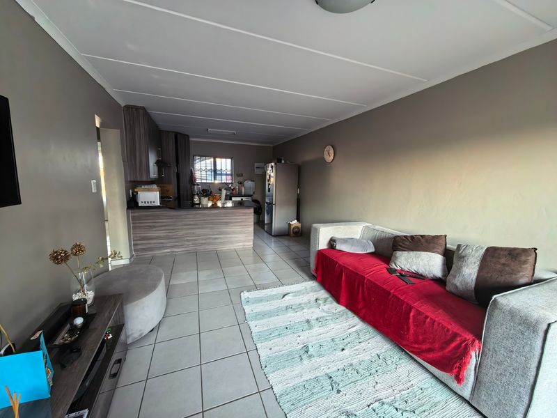Open-plan living area featuring tiled flooring and a functional kitchen with breakfast bar, providing a versatile space for dining and relaxation.