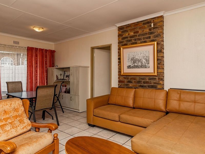 Open plan living and dining area featuring ceramic floor tiles and a prominent exposed brick fireplace feature wall.
