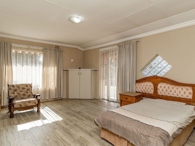 Spacious bedroom featuring laminate flooring, a built-in cupboard, and a unique diamond-shaped glass block window, offering a bright and functional living space.