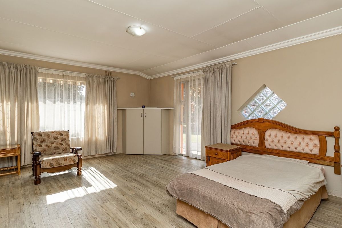 Spacious bedroom featuring laminate flooring, a built-in cupboard, and a unique diamond-shaped glass block window, offering a bright and functional living space.