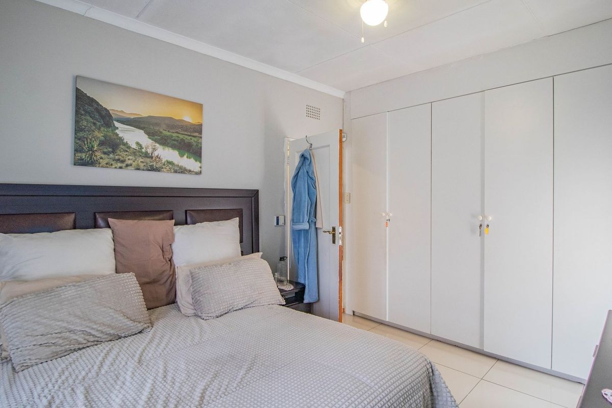 A well-maintained bedroom featuring neutral tiled flooring and extensive built-in cupboard storage.