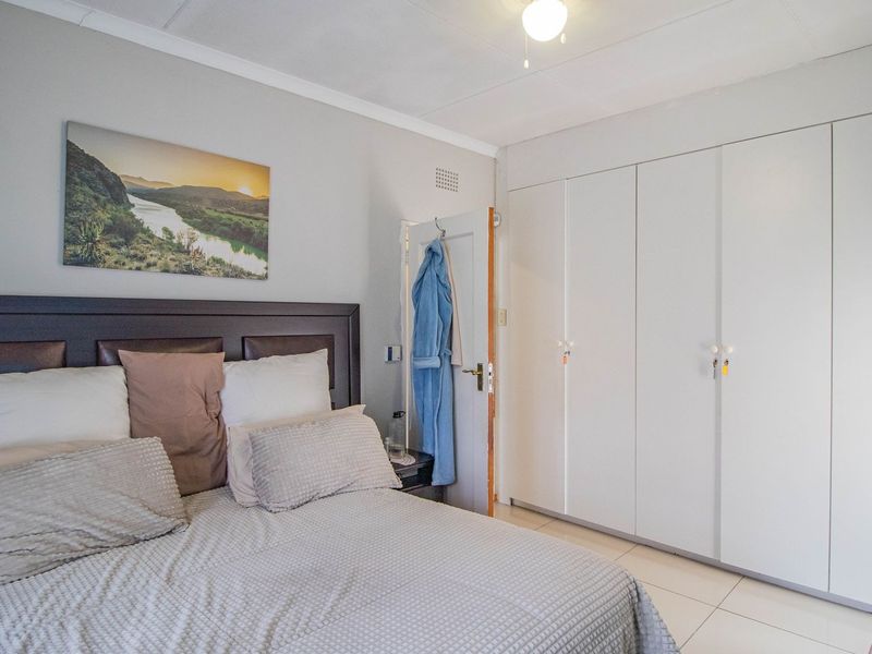 A well-maintained bedroom featuring neutral tiled flooring and extensive built-in cupboard storage.