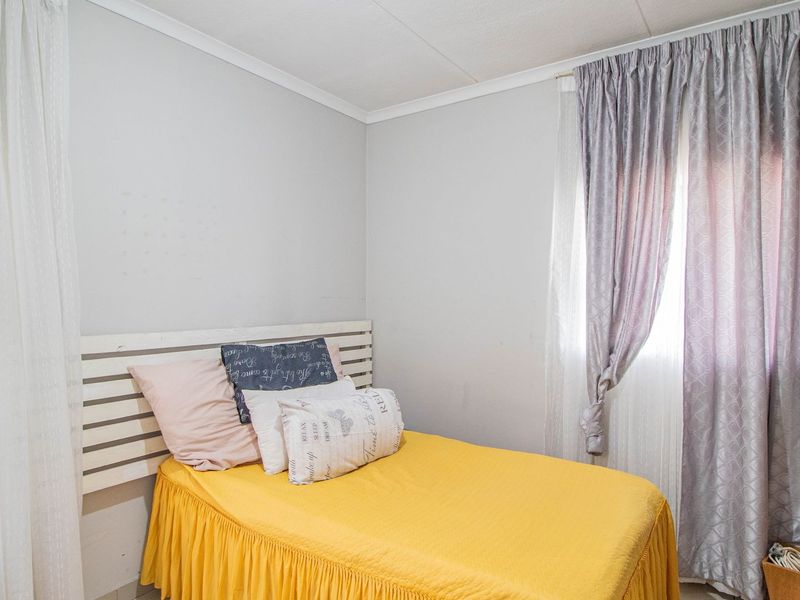 A standard bedroom featuring neutral wall finishes, tiled flooring, and window treatments.