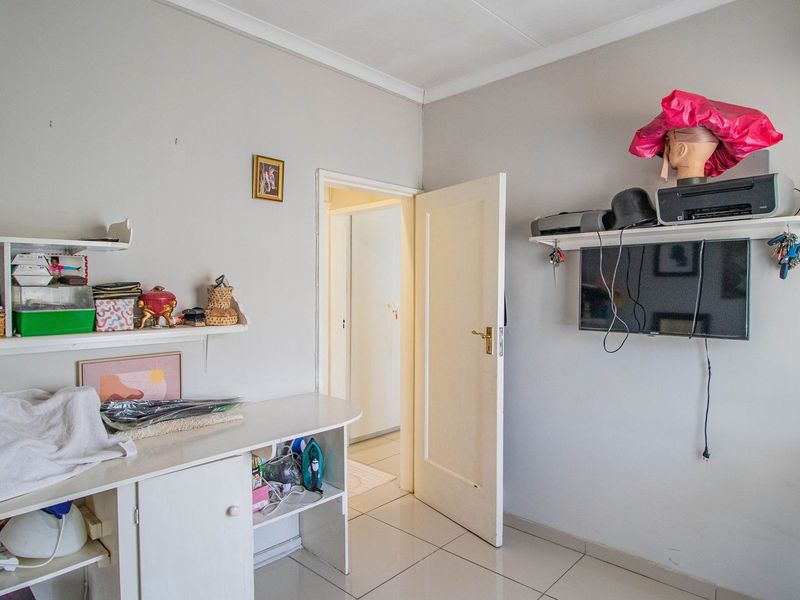 A bedroom featuring tiled flooring, built-in shelving units, and a standard internal door leading to an adjacent hallway.