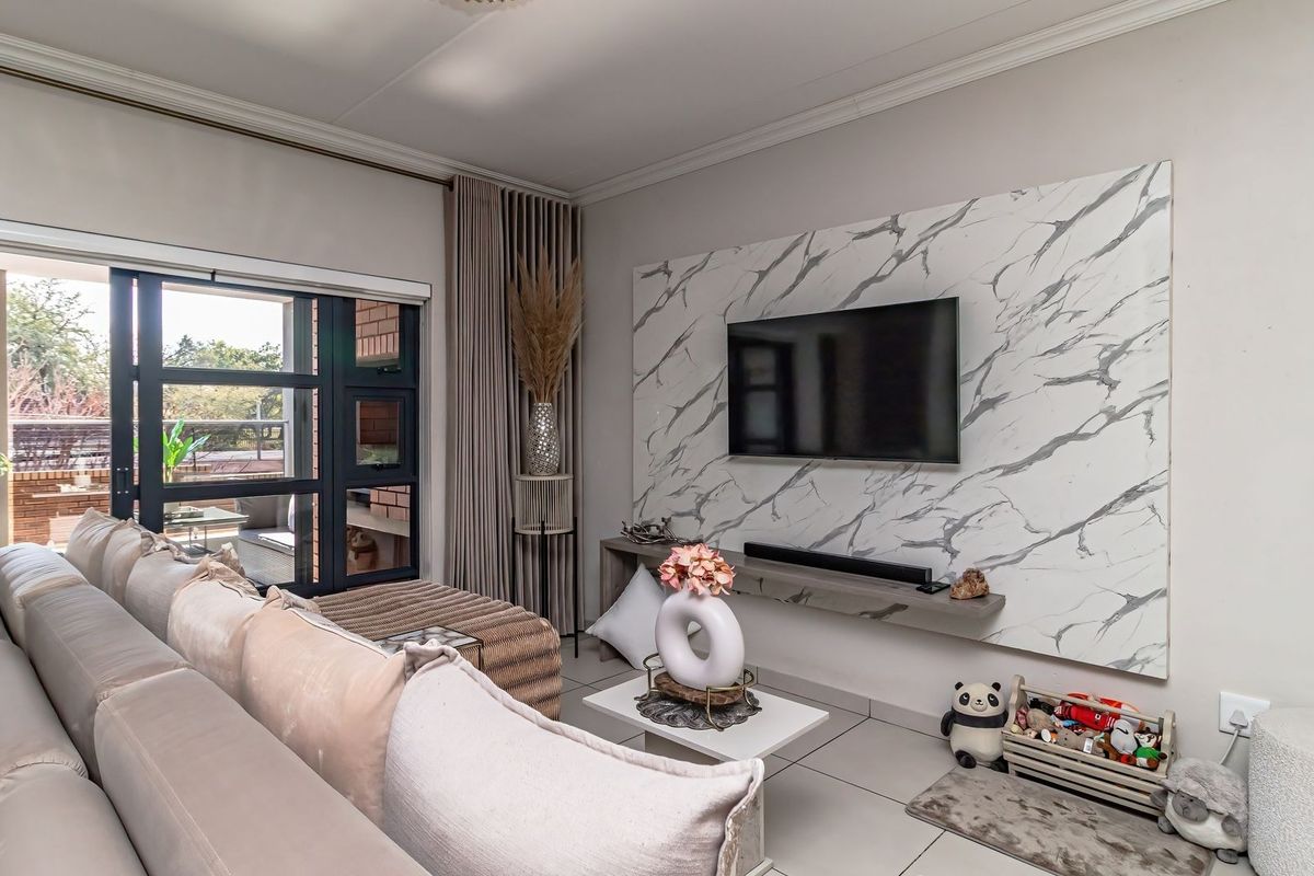 A well-maintained living room featuring a modern marble-effect feature wall, tiled flooring, and large sliding glass doors leading to an outdoor patio area.