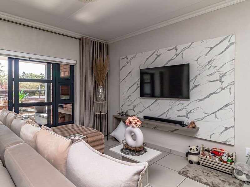 A well-maintained living room featuring a modern marble-effect feature wall, tiled flooring, and large sliding glass doors leading to an outdoor patio area.